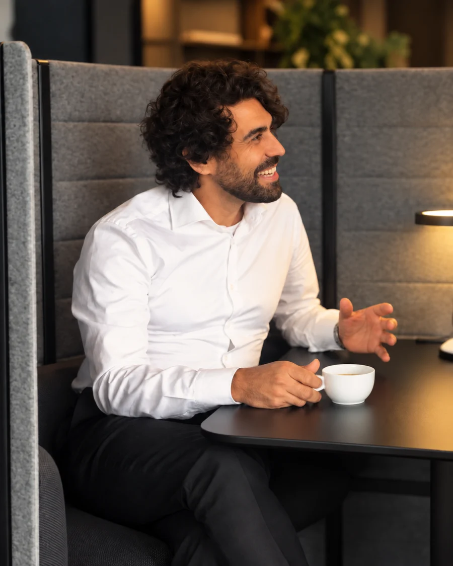 Leon Köllerwirth im Gespräch an einem Tisch, mit einer Kaffeetasse